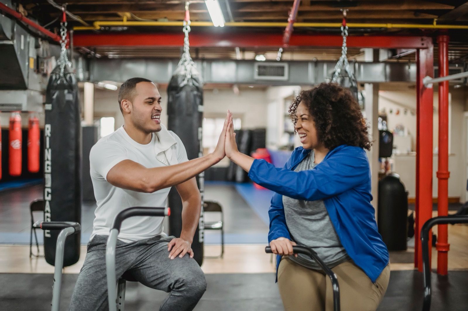 An instructor and client high-fiving mid-workout in a gym