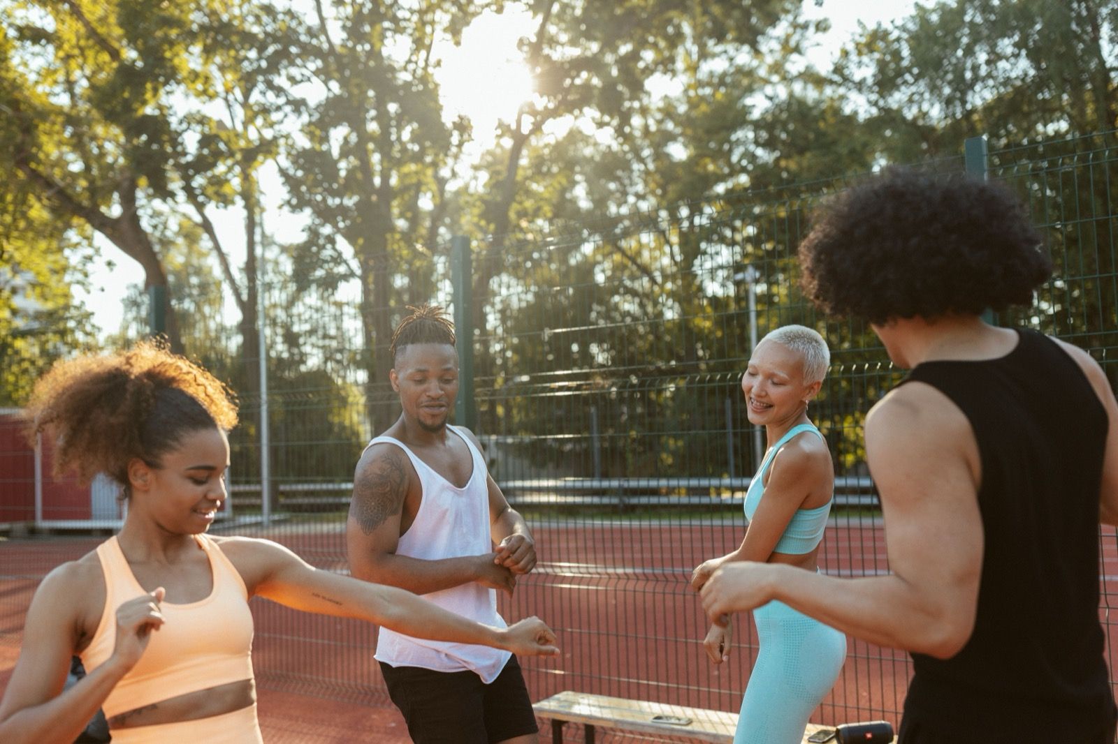 A group of people warming up together on an outdoor court at golden hour