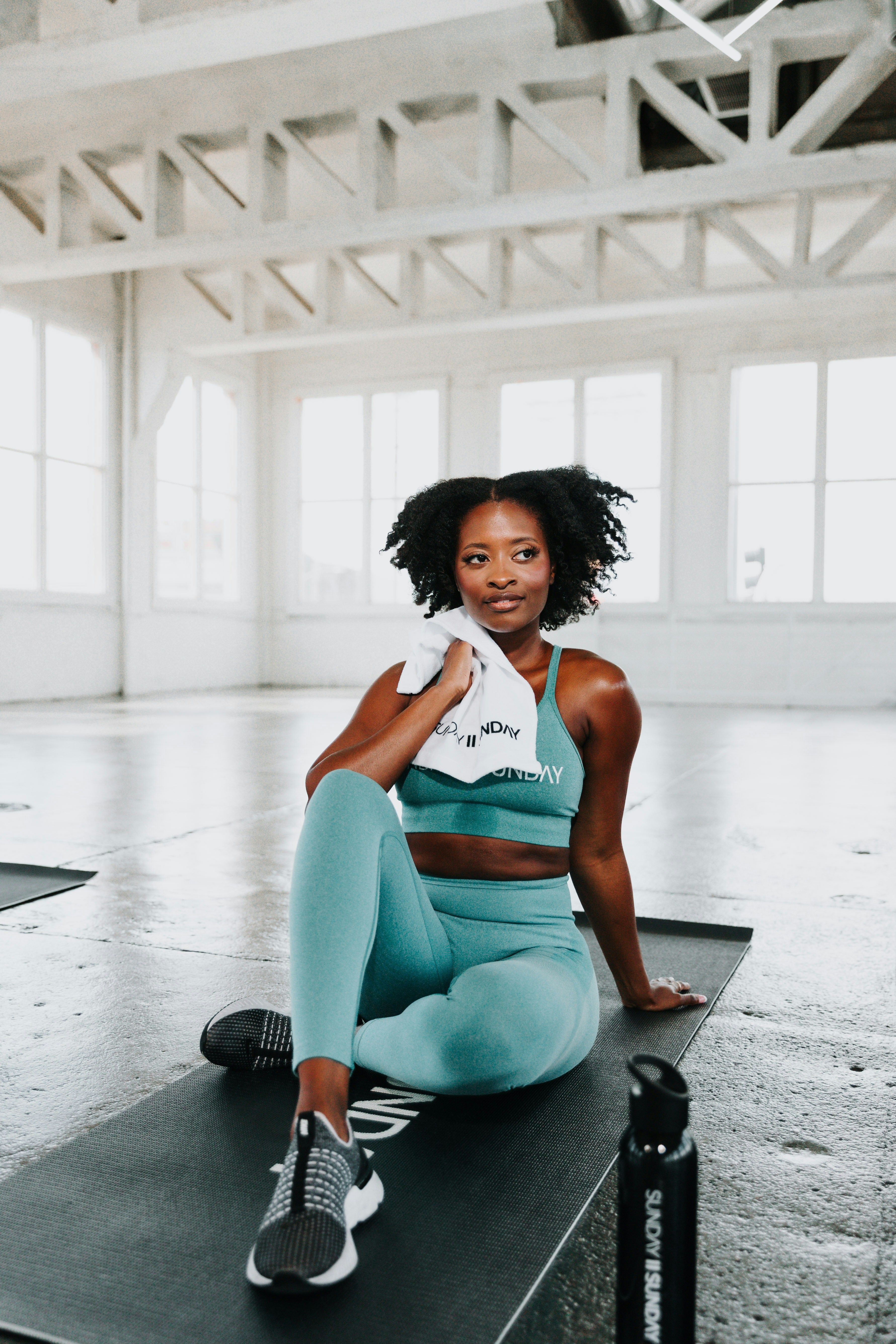 A fitness instructor resting on a mat in a bright studio